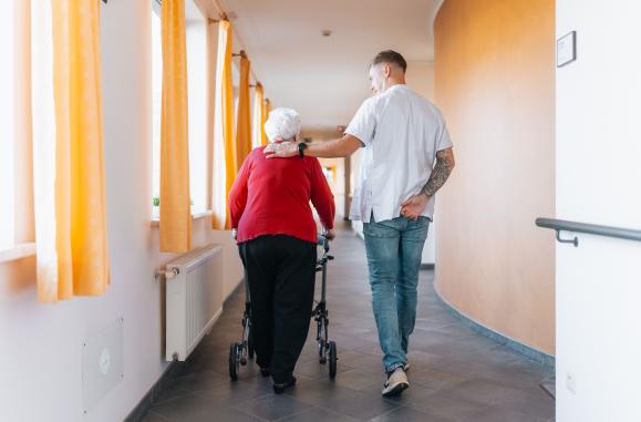 Verpleegkundige en patiënt, wandelend in de gang